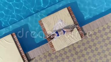 夏季，身着<strong>泳装</strong>的年轻女孩的鸟瞰景观就在泳池附近的露台上，那里有蓝色美丽的水